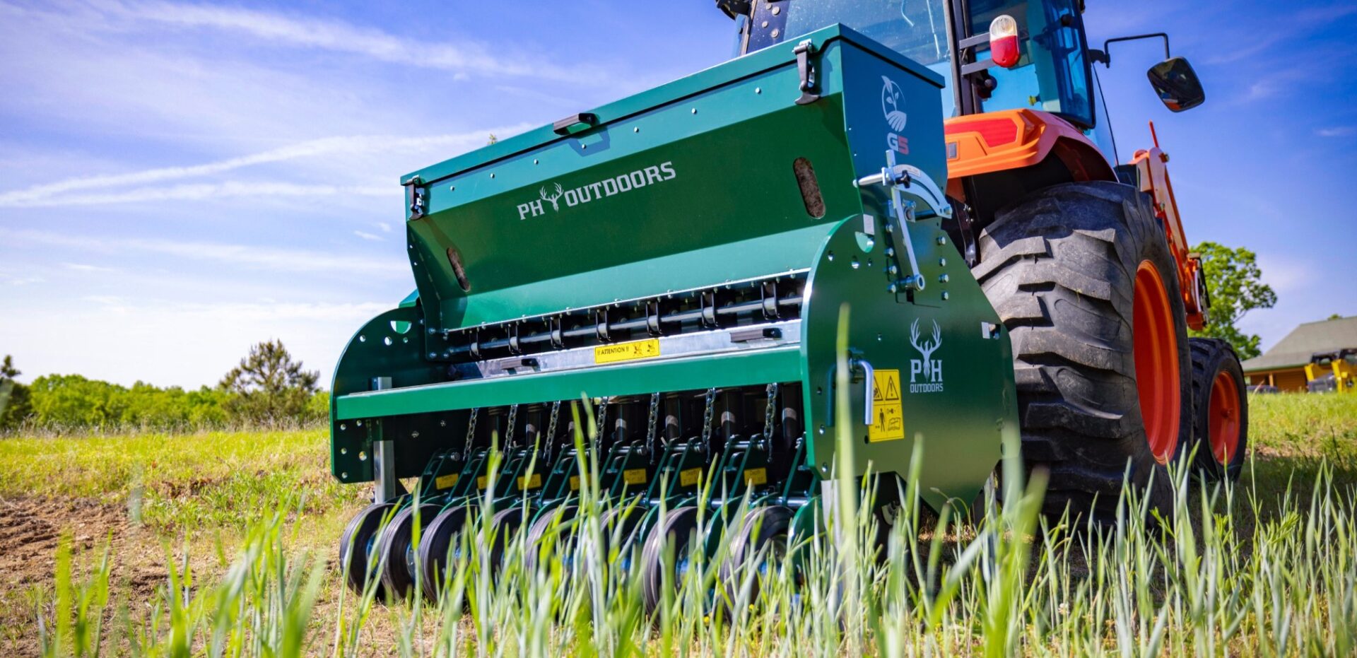PH Outdoors G5 no-till drill behind a tractor in a green field